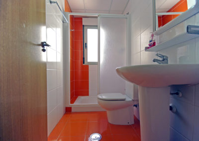 Baño con ducha y azulejos naranjas