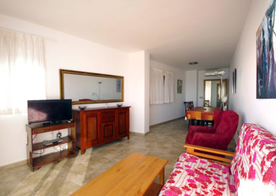 Salón comedor con televisión y mobiliario en apartamento vacacional